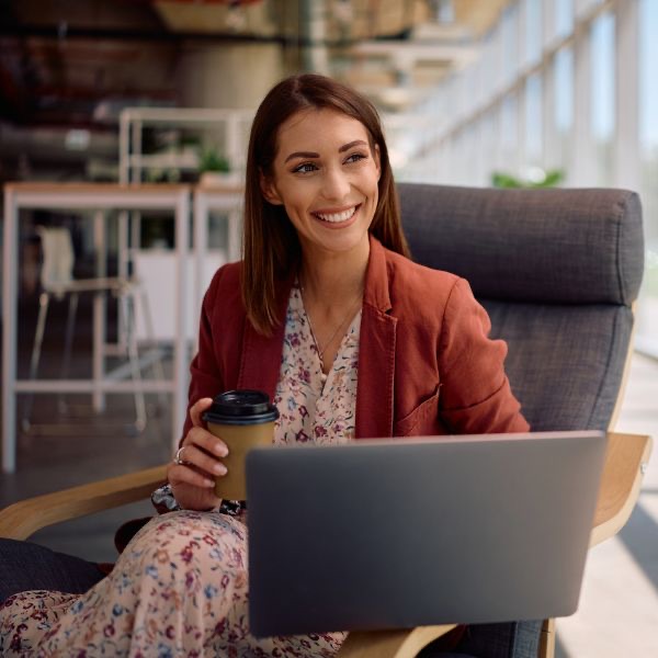 Smiling professional with laptop and coffee - SASE secure access service edge in action